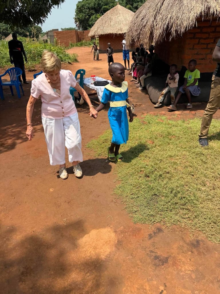 Mary McFarlane and Molly sharing a hug outside Molly's home in Uganda
