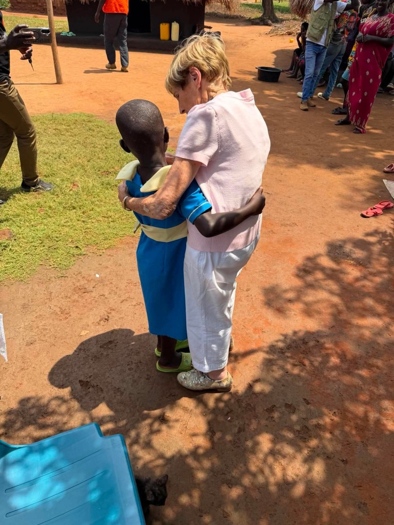 Mary McFarlane walking hand in hand with Molly in Molly's community in Uganda